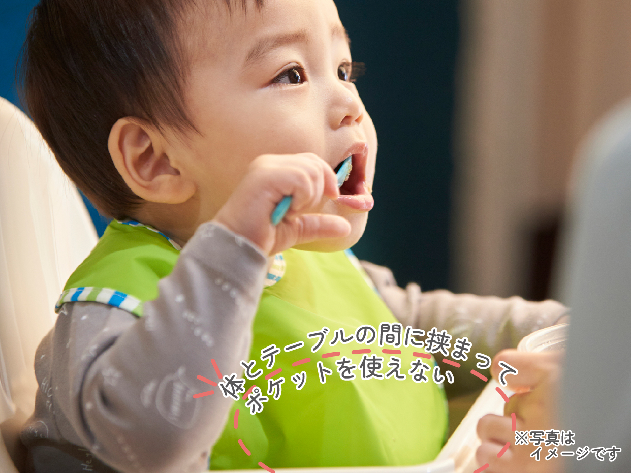 従来サイズのエプロンが長く、エプロンが体とテーブルの間に挟まってポケットが使えない様子